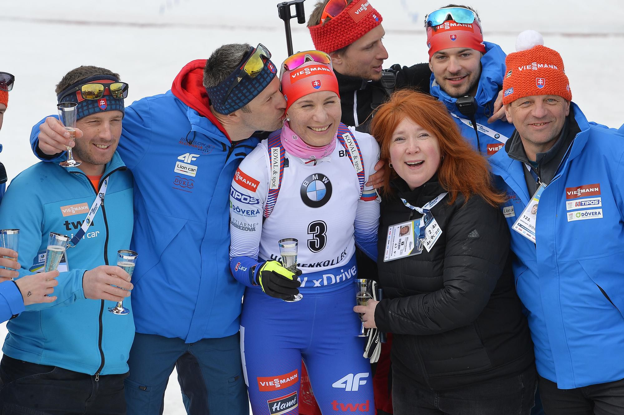 Slovenská biatlonistka Anastasia Kuzminová, naľavo ju bozkáva manžel Daniel s jej tímom a pretekármi počas rozlúčky s kariérou
