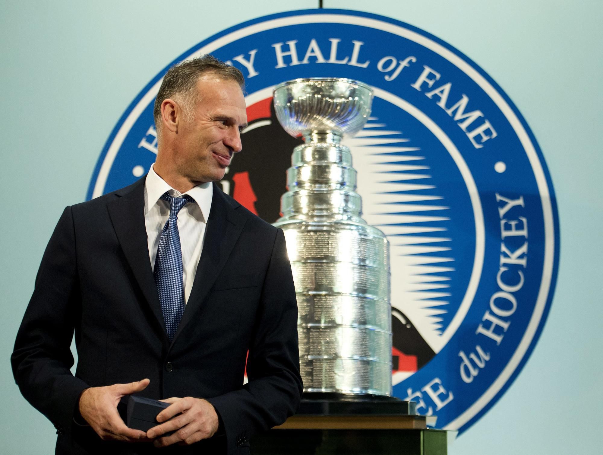 Čech Dominik Hašek sa usmieva pred Stanleyho pohárom v Sieni slávy NHL.