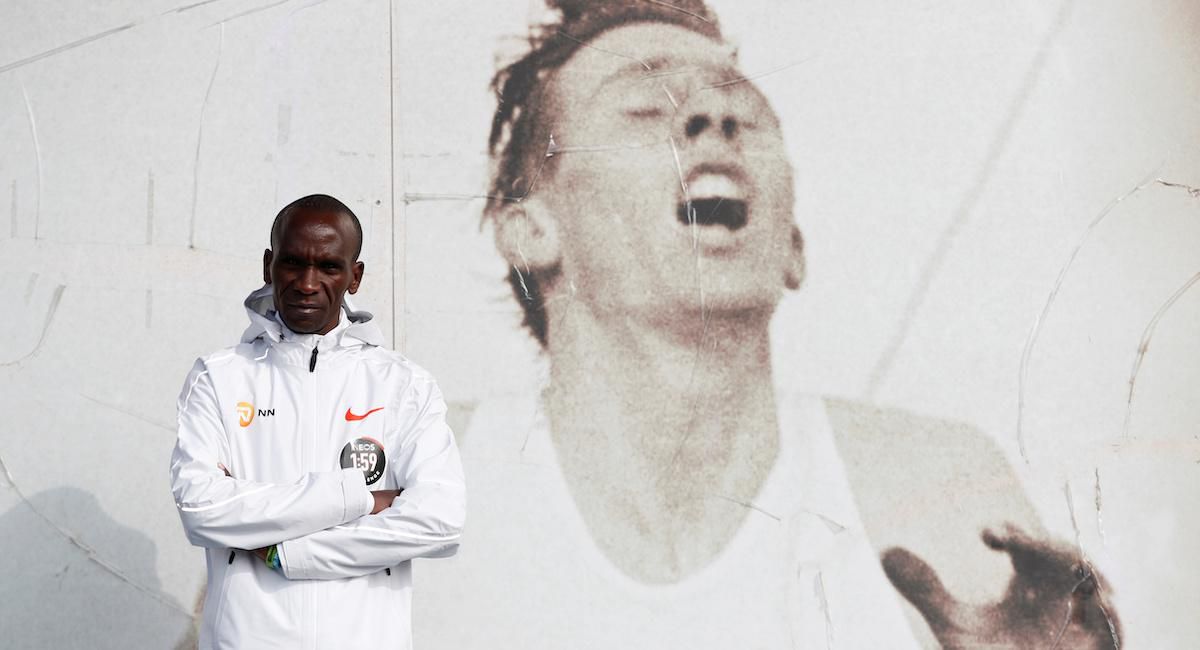 Eliud Kipchoge pred veľkým plagátom legendárneho Rogera Bannistera.