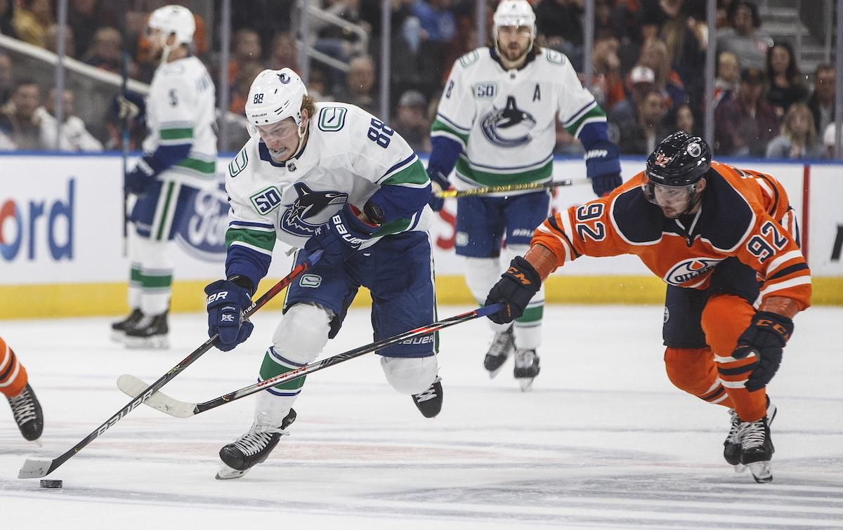 Slovenský obranca Oilers Tomáš Jurčo (vpravo) a hráč Canucks Adam Gaudette (vľavo) v súboji o puk v prípravnom zápase Edmonton Oilers - Vancouver Canucks