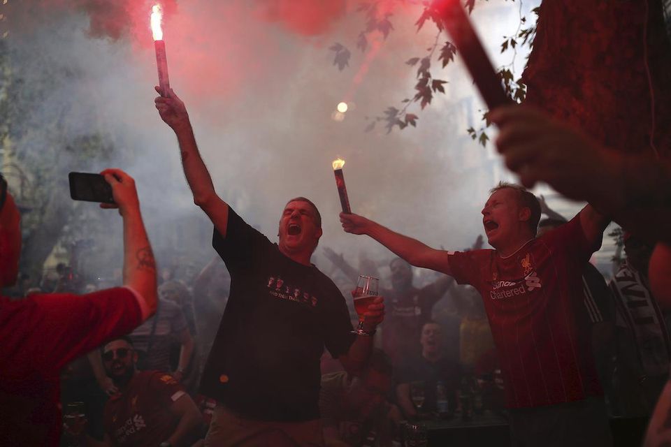 Fanúšikovia Liverpoolu skandujú so svetlicami.