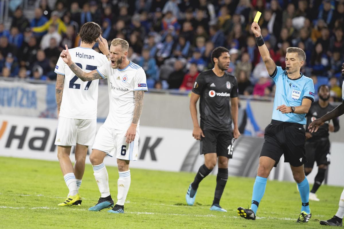 Hlavný rozhodca Kristo Tohver udeľuje žltú kartu, druhý zľava potrestaný Joeri De Kamps (Slovan).