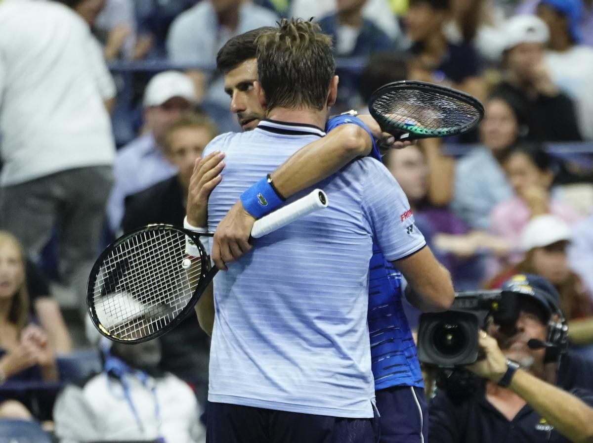 Srbský tenista Novak Djokovič (otočený tvárou) objíma Švajčiara Stana Wawrinku.