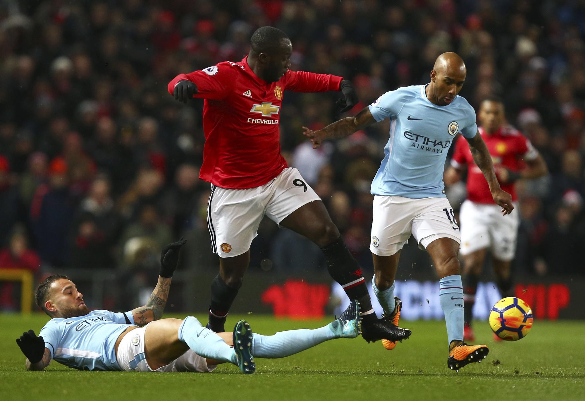 Futbalista Manchestru United Romelu Lukaku (uprostred), hráči Manchestru City Nicolas Otamendi (vľavo) a Fabian Delph bojujú o loptu.