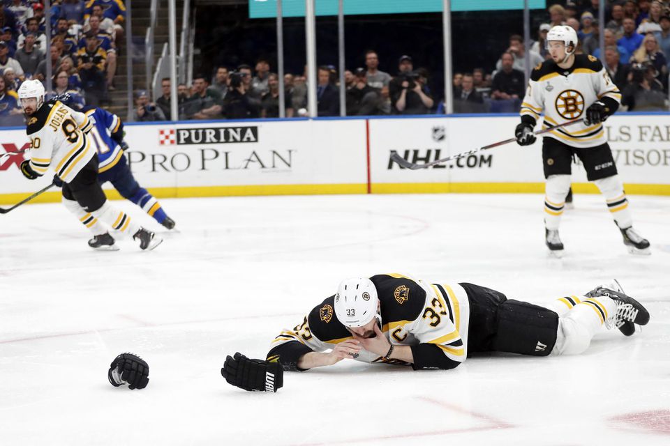 Kapitán Bostonu Bruins Zdeno Chára leží na ľade po zásahu pukom.
