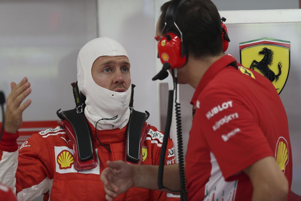 Sebastian Vettel (Ferrari) sa rozpráva s technikom v boxoch