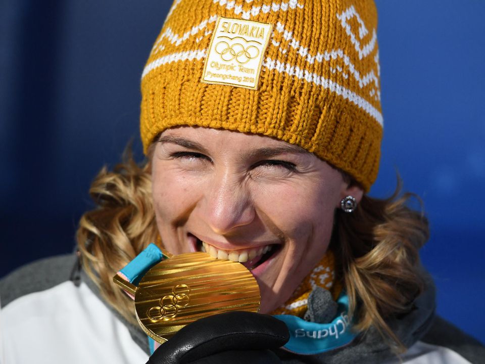 Anastasia Kuzminová hryzie zlatú medailu, ktorú získala v pretekoch s hromadným štartom na 12,5 km.