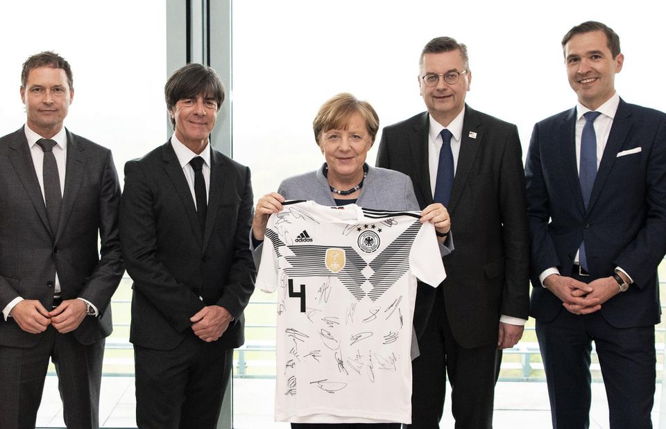 Angela Merkelová s trénerom Joachimom Löwom drží nemecký dres s číslom 4