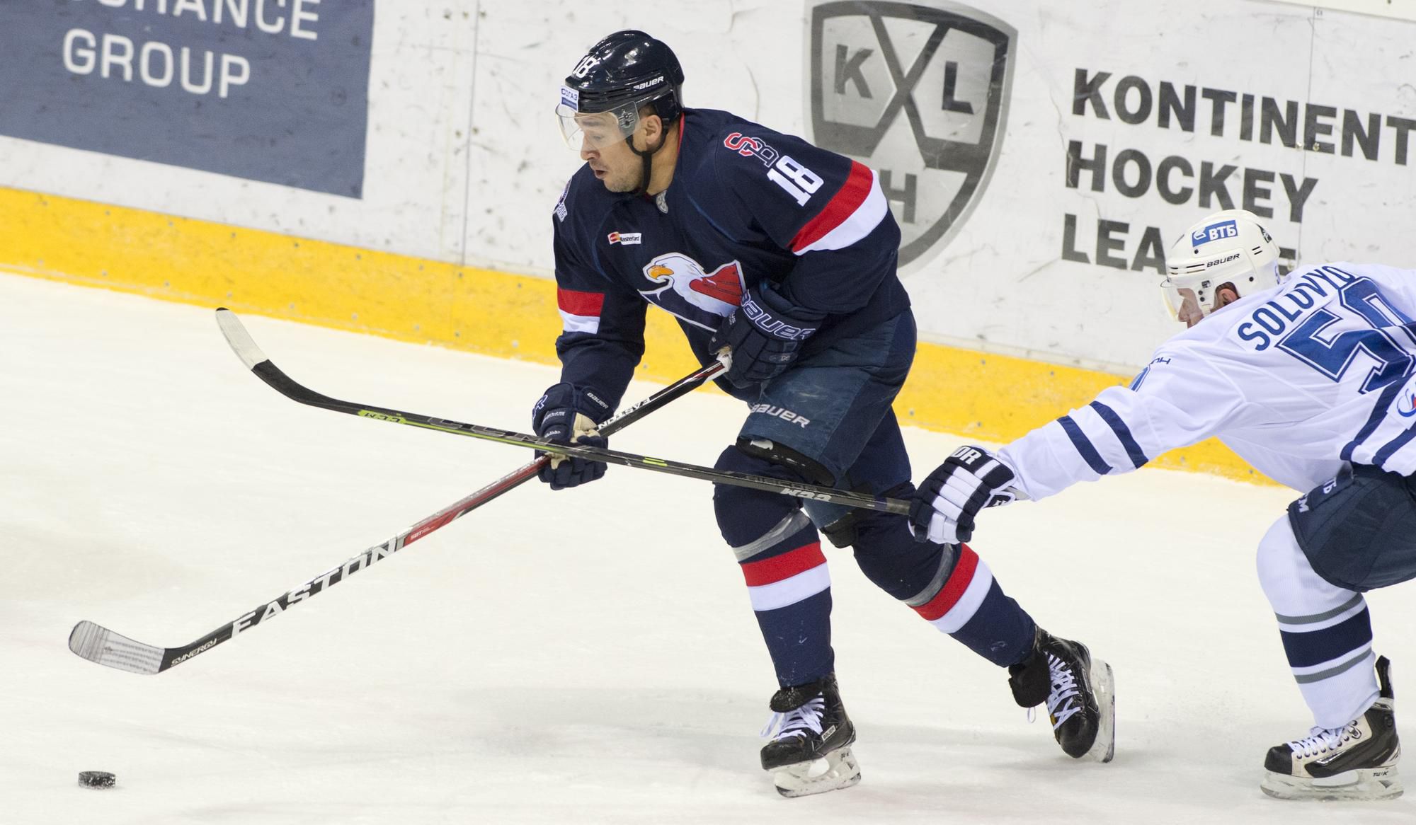 Jonathan Cheechoo (Slovan) a vpravo Maxim Solovjov (Dinamo) v hokejovej KHL.