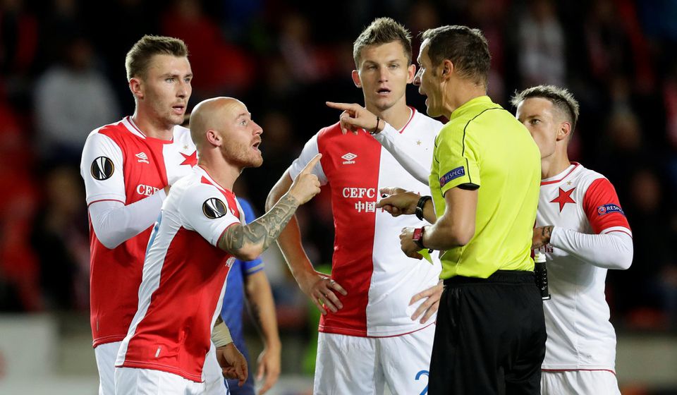 Hráči Slavie Praha diskutujú s rozhodcom počas zápasu EL.