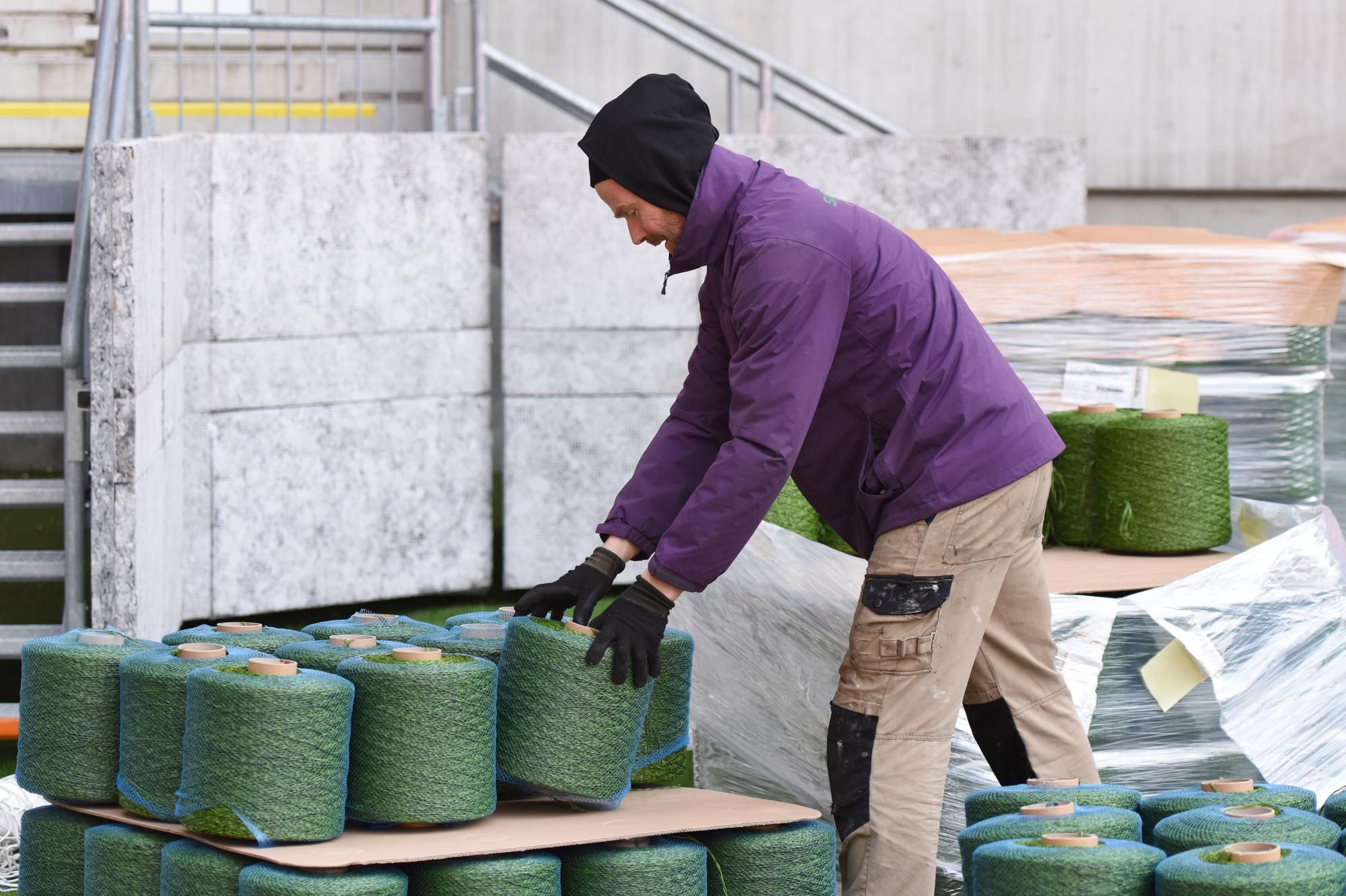 pracovník pripravuje umelé vlákna, ktoré sa všívajú do prírodného trávnika