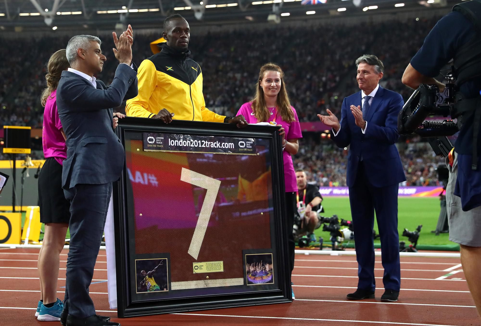 Usain Bolt preberá zarámovaný kus atletickej dráhy londýnskeho štadióna, ktorý dostal na pamiatku po svojich posledných pretekoch.
