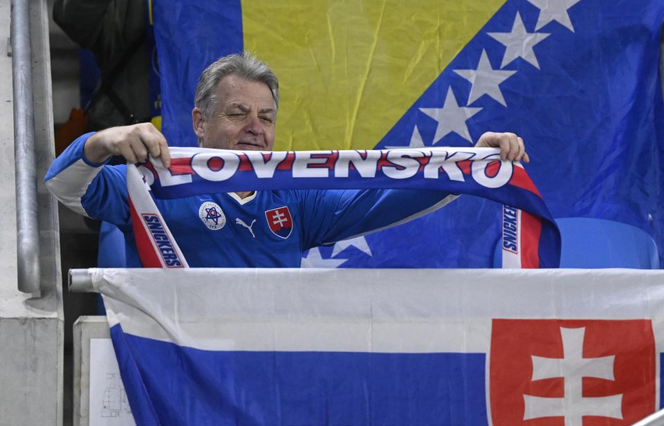 Fanúšik Slovenska stojí pred vlajkou Bosny a Hercegoviny