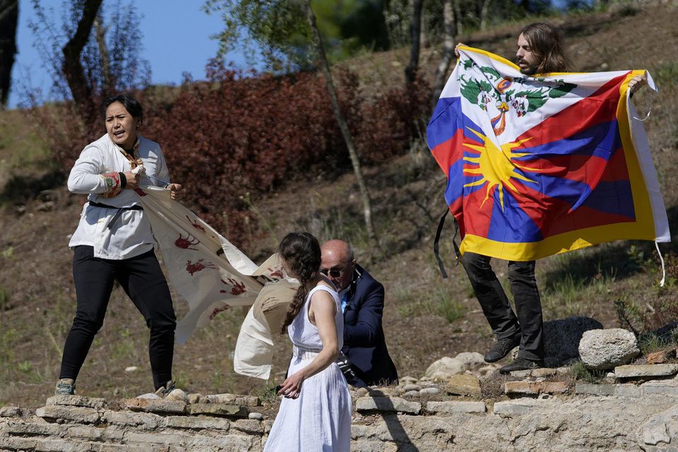 Protestujúci s tibetskou vlajkou a transparentom počas zapálenia olympijského ohňa