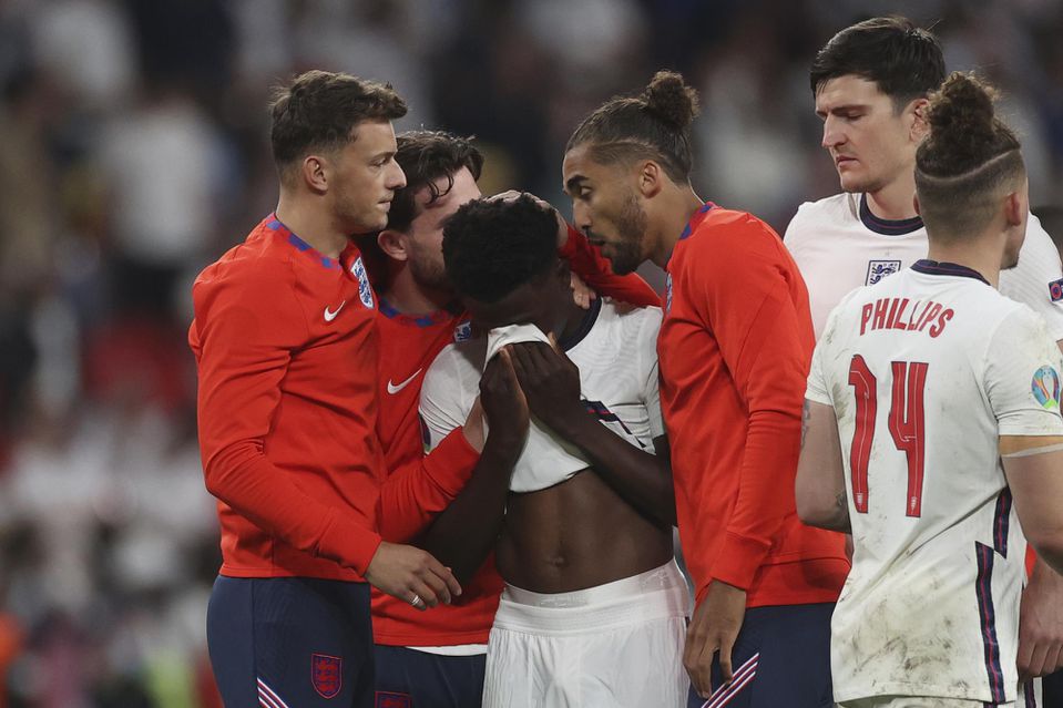 Bukayo Saka v objatí spoluhráčov z Anglicka po nepremenenej penalte vo finále EURO 2020