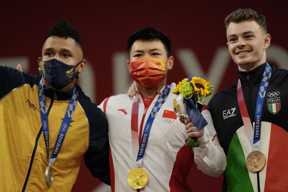 Čínsky vzpierač Čchen Li-ťün (uprostred) získal zlatú olympijskú medailu.