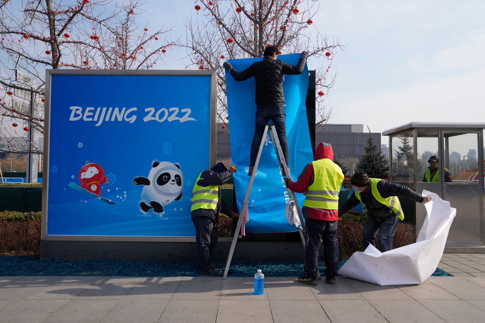 A téli játékokat népszerűsítő plakátot ragasztanak ki a pekingi Olimpiai Parkban 2022. január 18-án / Fotó: MTI/AP