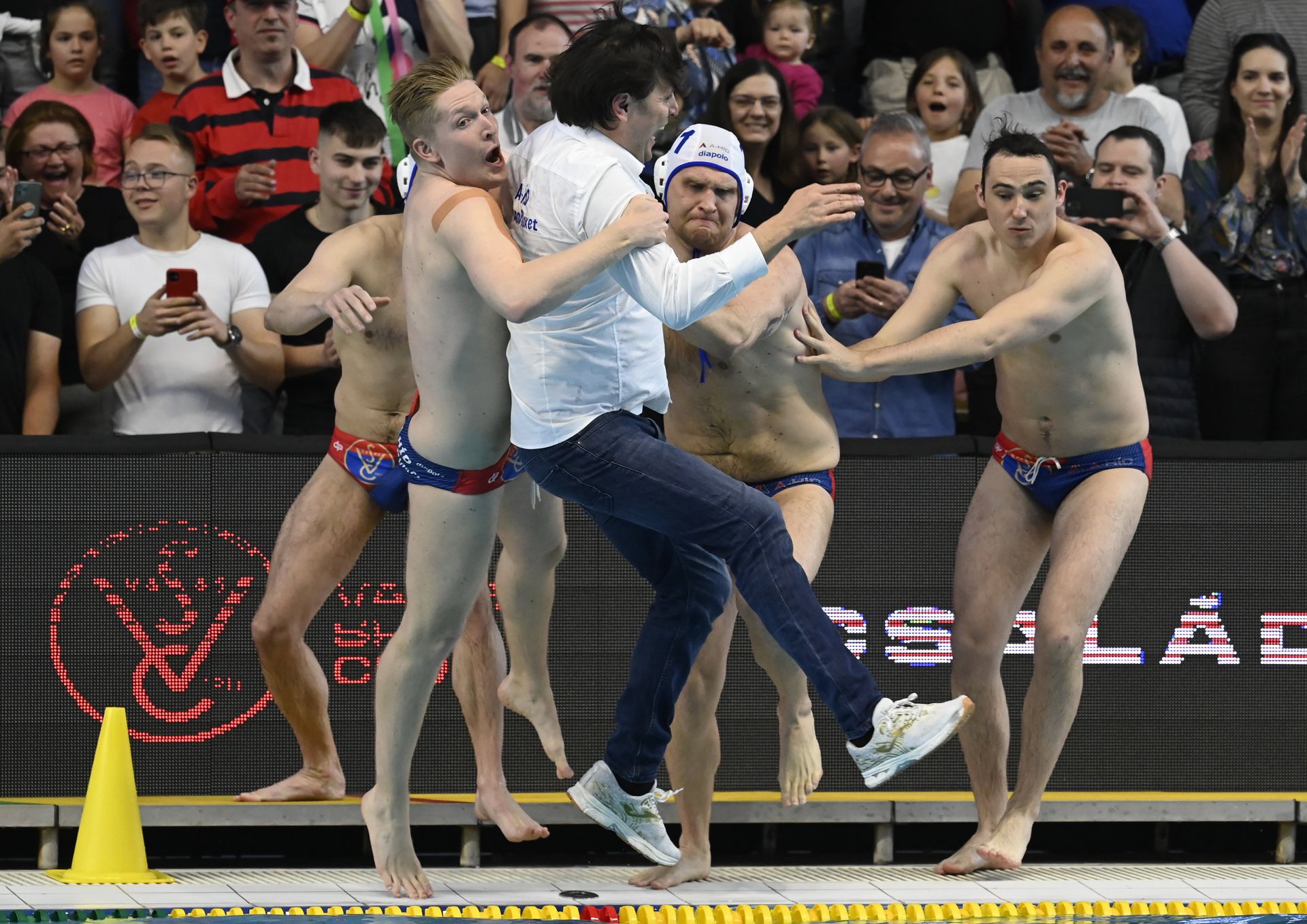 Szlobodan Nikicset, a Vasas vezetőedzőjét a vízbe dobják a győztes angyalföldi játékosok. Fotó: MTI/Kovács Tamás