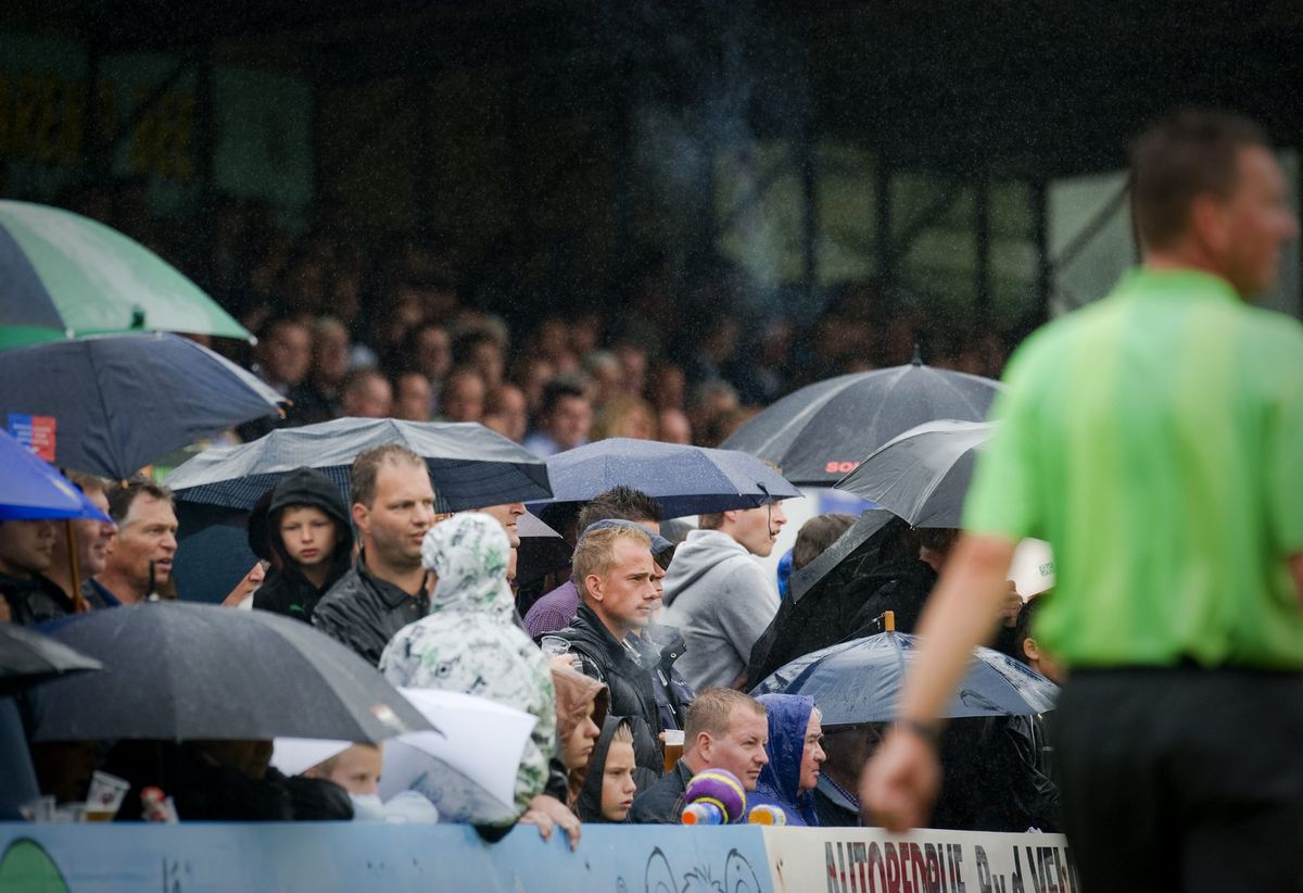 Toeschouwers takelen voetballers toe met paraplu