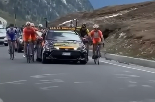 🎥😱 | Deze beelden: Giro straft 24 renners nadat ze hangend aan auto berg op gaan