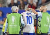 Kylian Mbappé met twee leden van de medische staf / Getty Images